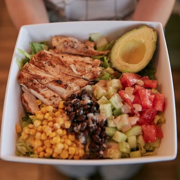A John's Place salad with grilled chicken, corn, black beans, avocado, tomatoes, and cucumbers.