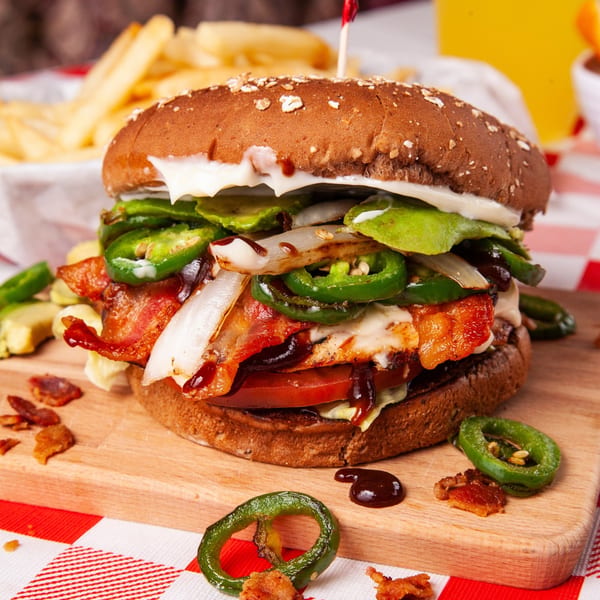 A John's Place burger with bacon, jalapeños, onions, and avocado, served with fries.