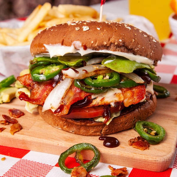 A John's Place burger with bacon, jalapeños, onions, and sauce, served with fries.